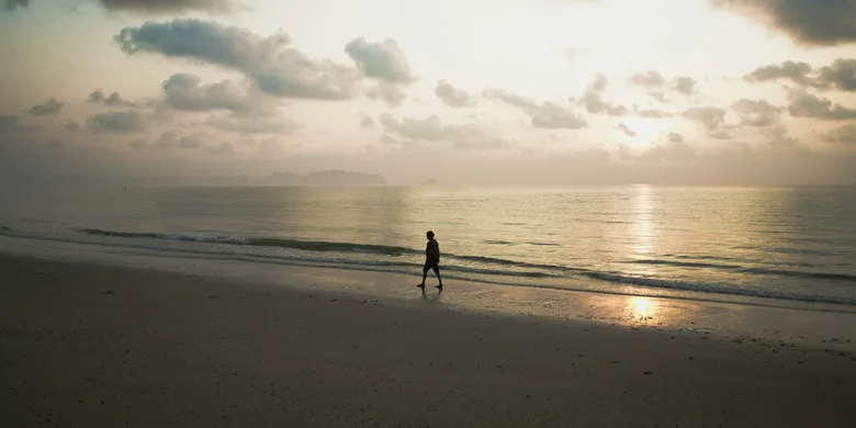 Una persona camina por la orilla del mar al amanecer